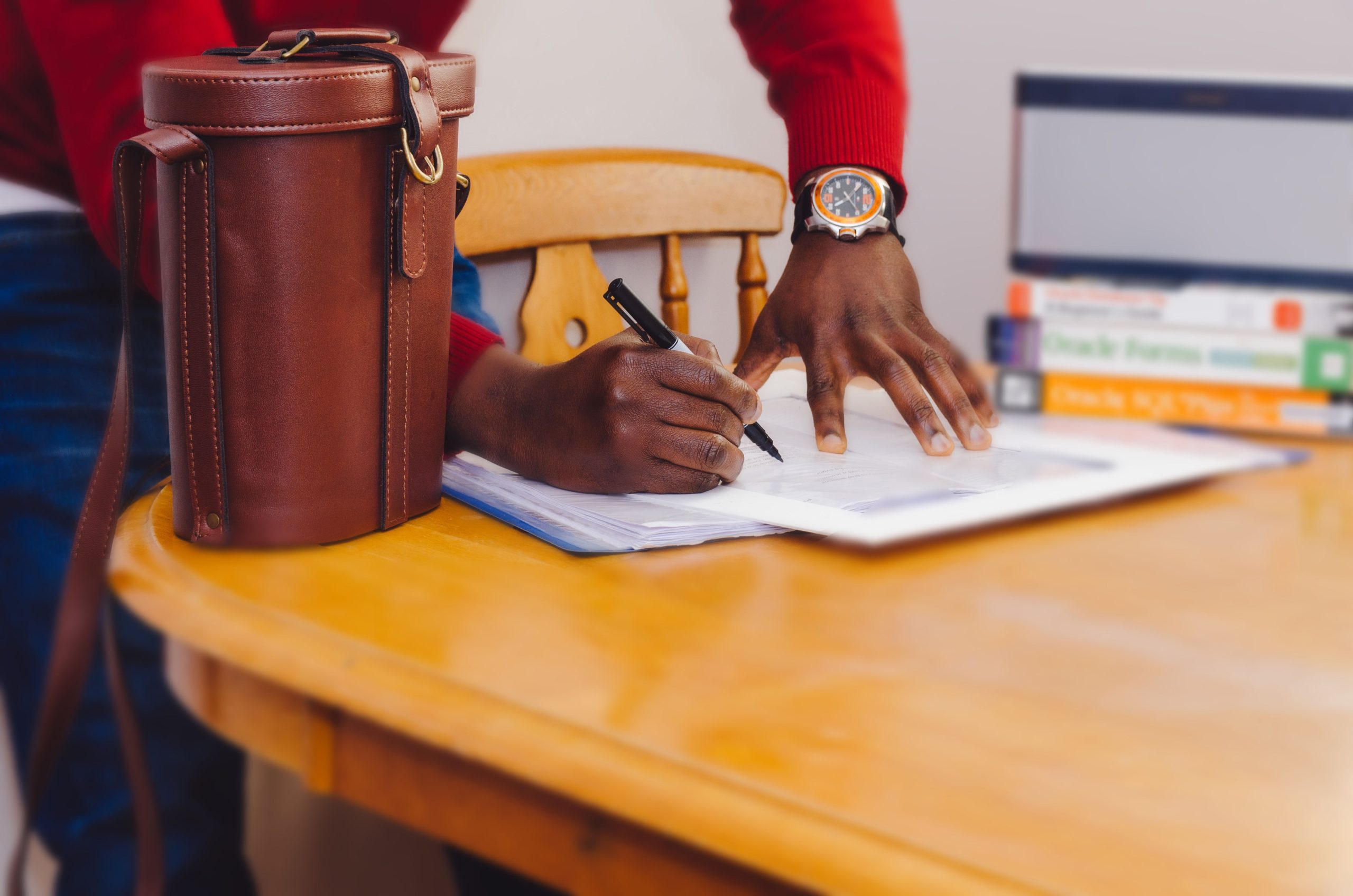 A close up of a person's hands writing something on a paper on a table.