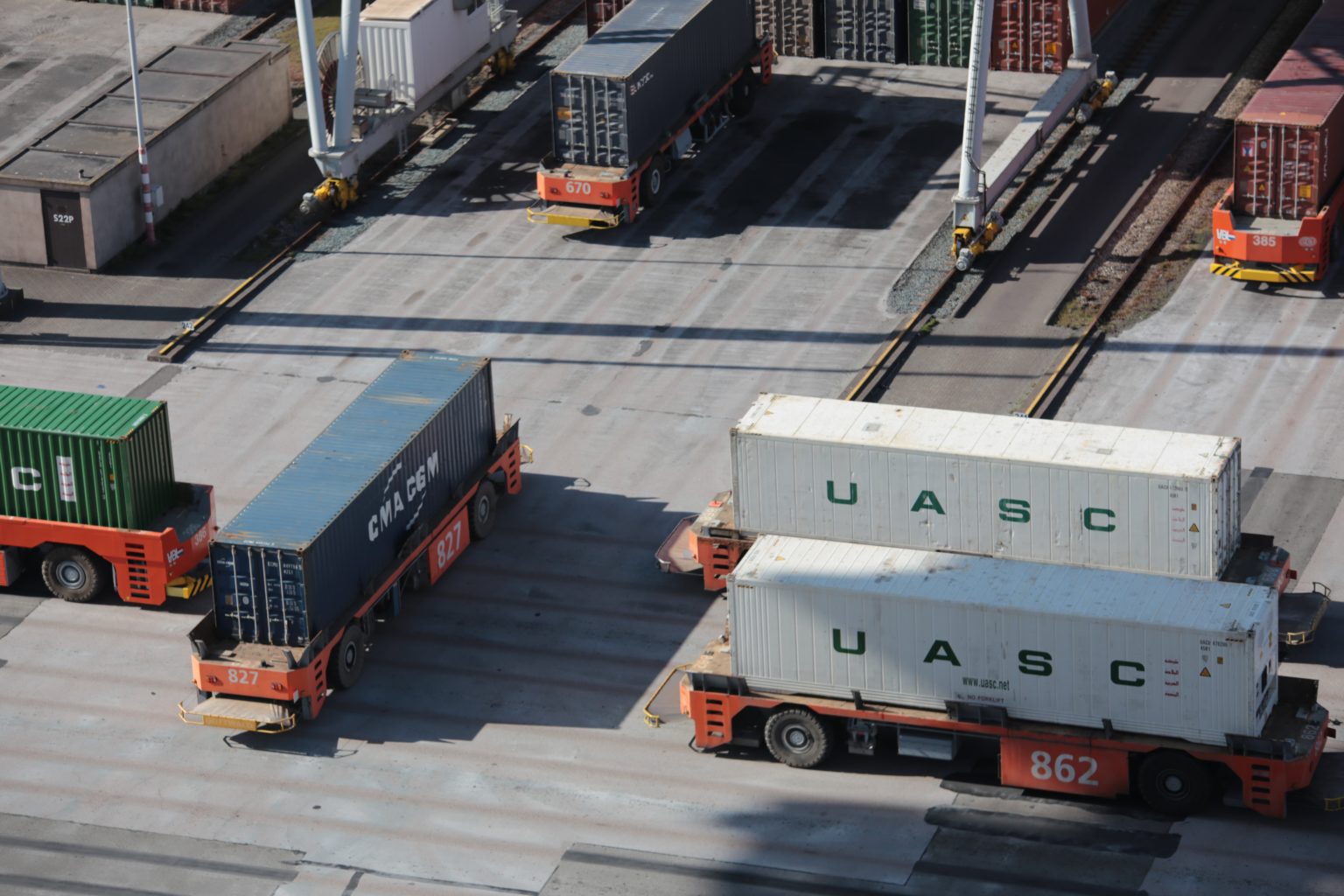 Flatbed trailers each with a loaded shipping container.