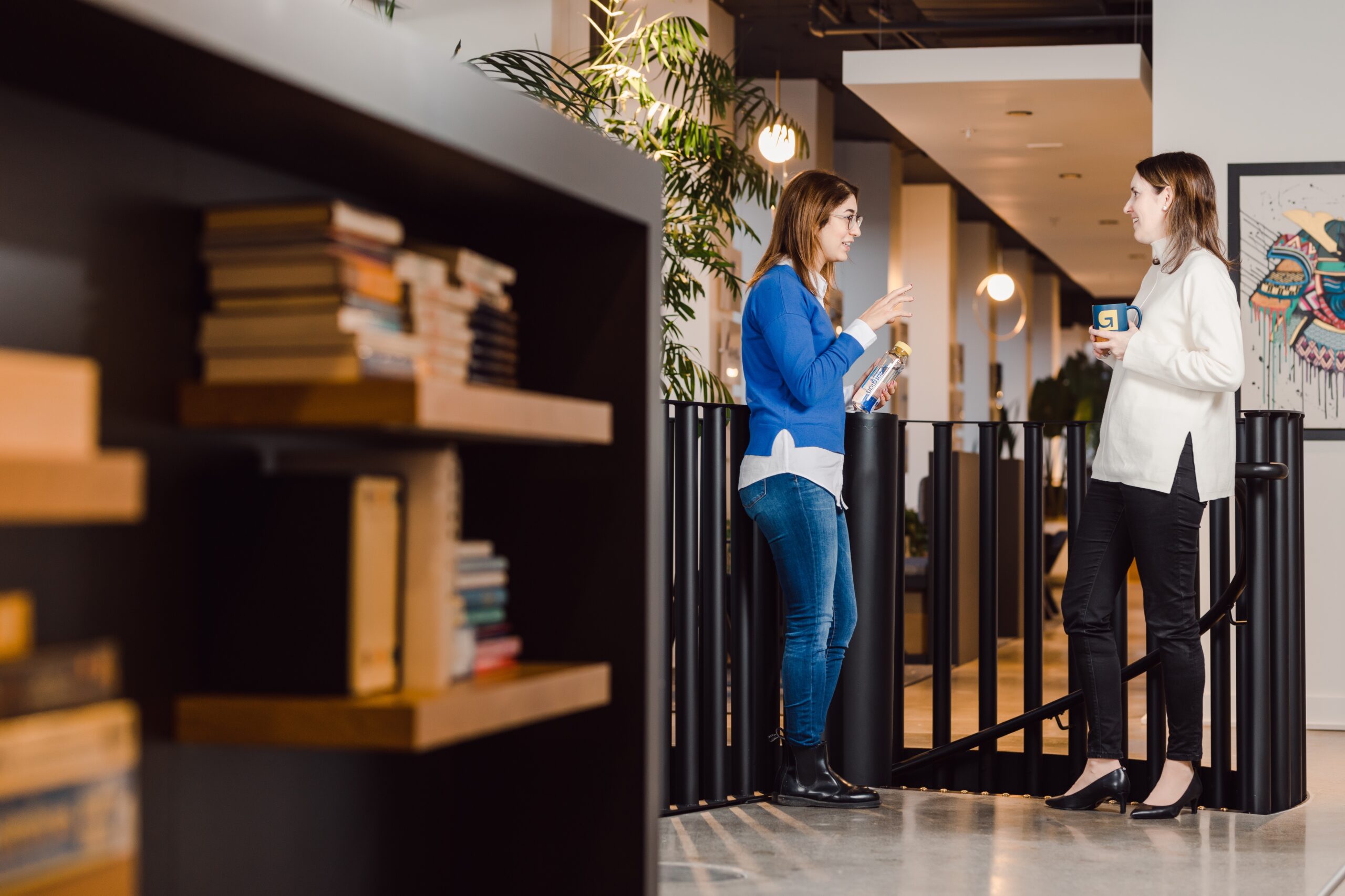 Full body shot of co-workers chatting in the hallway